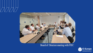 Group of directors around a long conference table in a meeting room, laptops and papers visible, discussing at a formal board meeting (FIEC)