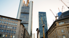 City skyline with tall glass skyscrapers and construction cranes at a developing site during building work for a modern downtown area.
