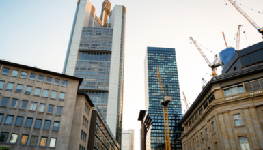 City skyline with tall glass skyscrapers and construction cranes at a developing site during building work for a modern downtown area.
